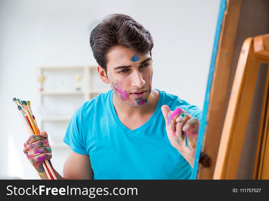 The young funny artist working on new painting in his studio