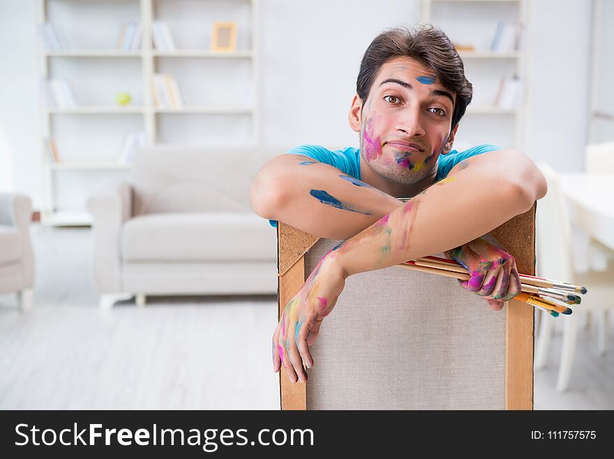 The young funny artist working on new painting in his studio