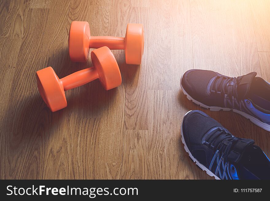Sneakers and dumbbells fitness on a wooden background. Different tools for sport