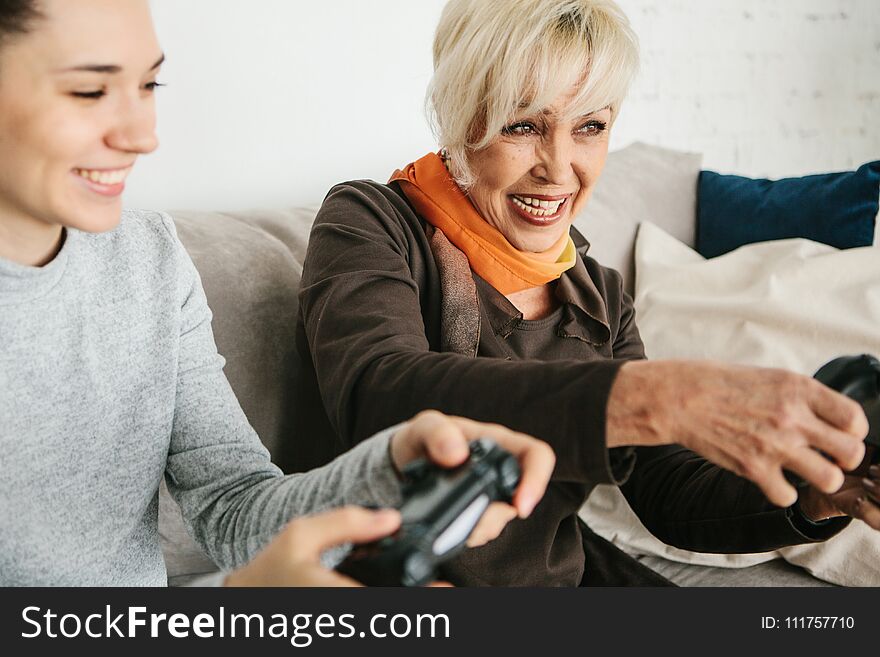 A young girl and an elderly women play together in a video game. Joint pastime. Family life. Communication of the grandmother with her granddaughter. A young girl and an elderly women play together in a video game. Joint pastime. Family life. Communication of the grandmother with her granddaughter