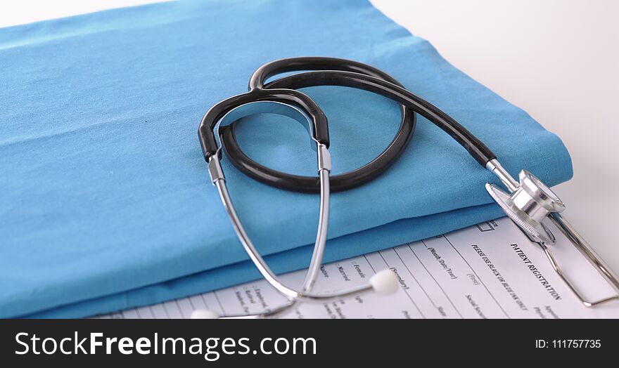 A stethoscope shaping a heart on a medical uniform, closeup.