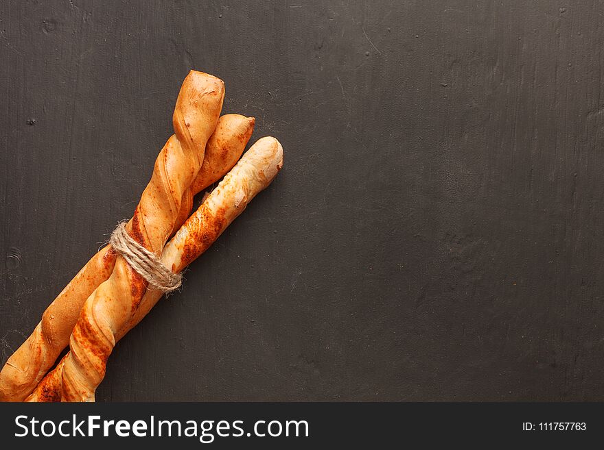 Three baguettes tied by jute twine on dark background with copyspace. Top view. Three baguettes tied by jute twine on dark background with copyspace. Top view