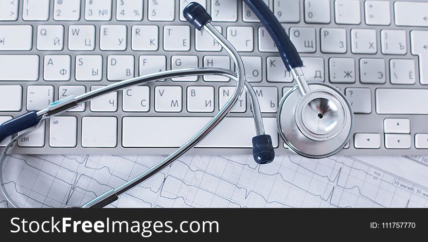 A stethoscope is on the keyboard of a computer.