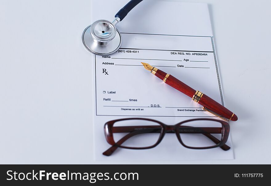 Doctor`s workspace working table with patient`s discharge blank paper form, medical prescription, stethoscope on desk.