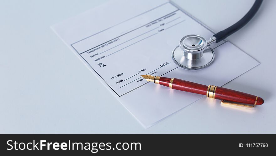 Doctor`s workspace working table with patient`s discharge blank paper form, medical prescription, stethoscope on desk.