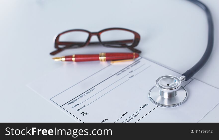 Doctor`s workspace working table with patient`s discharge blank paper form, medical prescription, stethoscope on desk