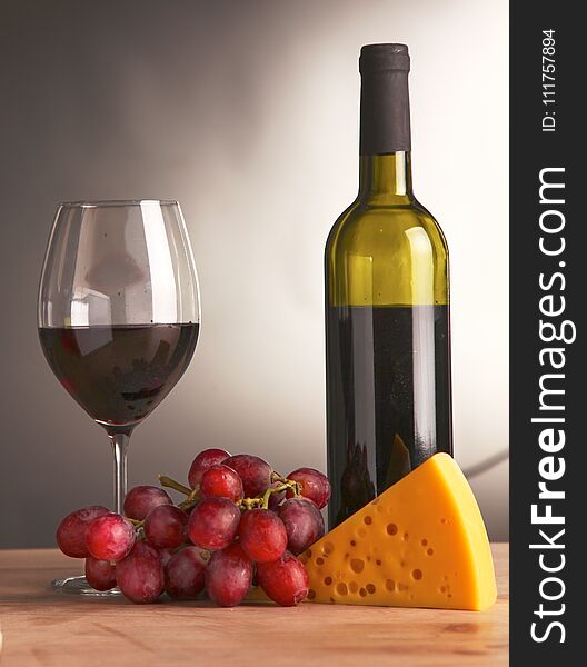 Still life with glass and bottle of wine, cheese and grapes.