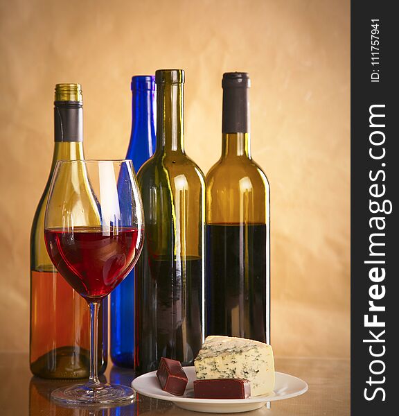 Still life with glass and bottle of wine, cheese and grapes.