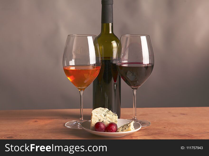 Still life with glass and bottle of wine, cheese and grapes.