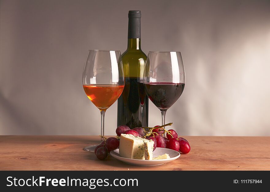 Still life with glass and bottle of wine, cheese and grapes.