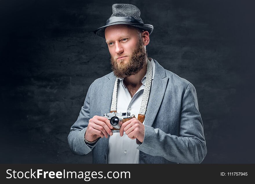 Bearded male holds vintage slr photo camera.