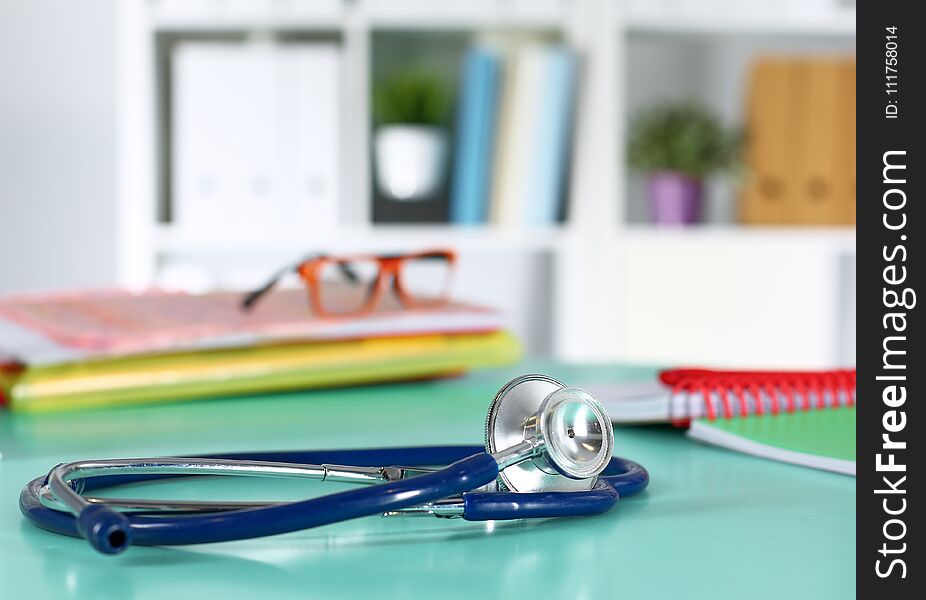 Doctor`s workspace working table with patient`s discharge blank paper form, medical prescription, stethoscope on desk