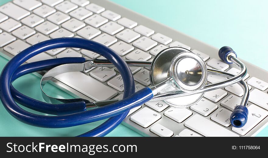 A stethoscope is on the keyboard of a computer.