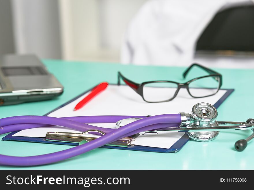 Doctor`s workspace working table with patient`s discharge blank paper form, medical prescription, stethoscope on desk.