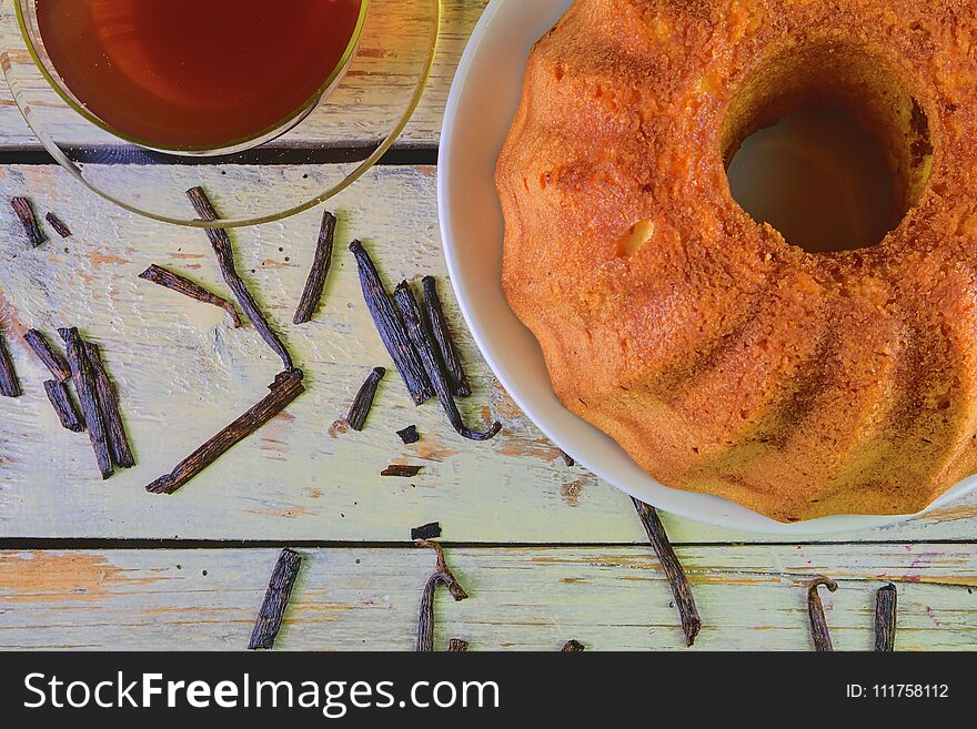 Old fashioned sand cake with cup of black tea and pieces of vanilla on wooden background. Egg-yolk sponge cake on rustic