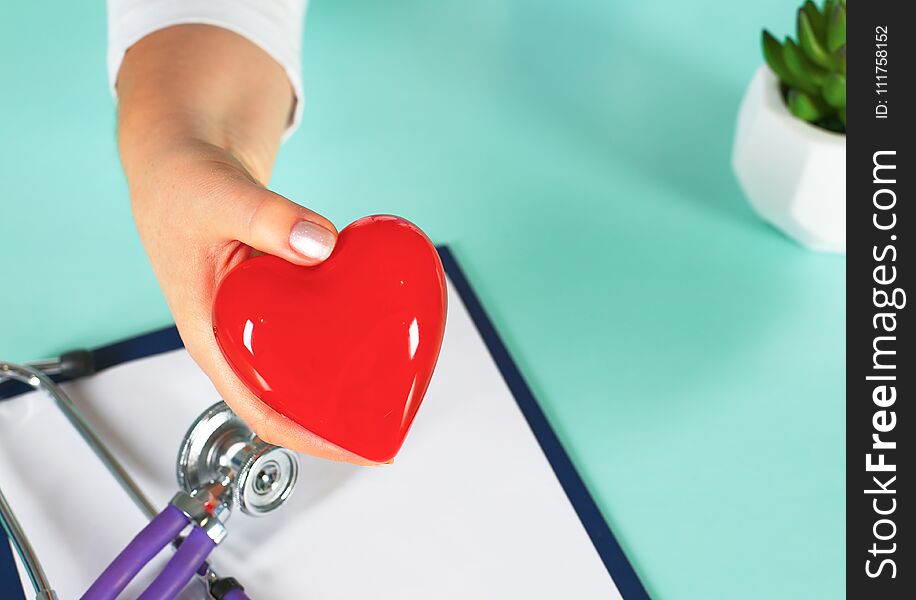 Female doctor with the stethoscope holding heart