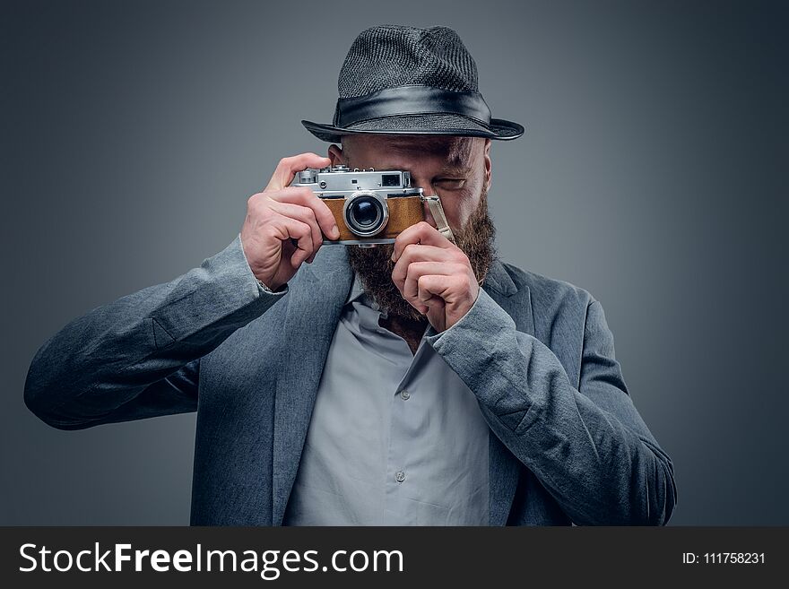 Bearded male in the felt hat shooting with the vintage SLR photo camera. Bearded male in the felt hat shooting with the vintage SLR photo camera.