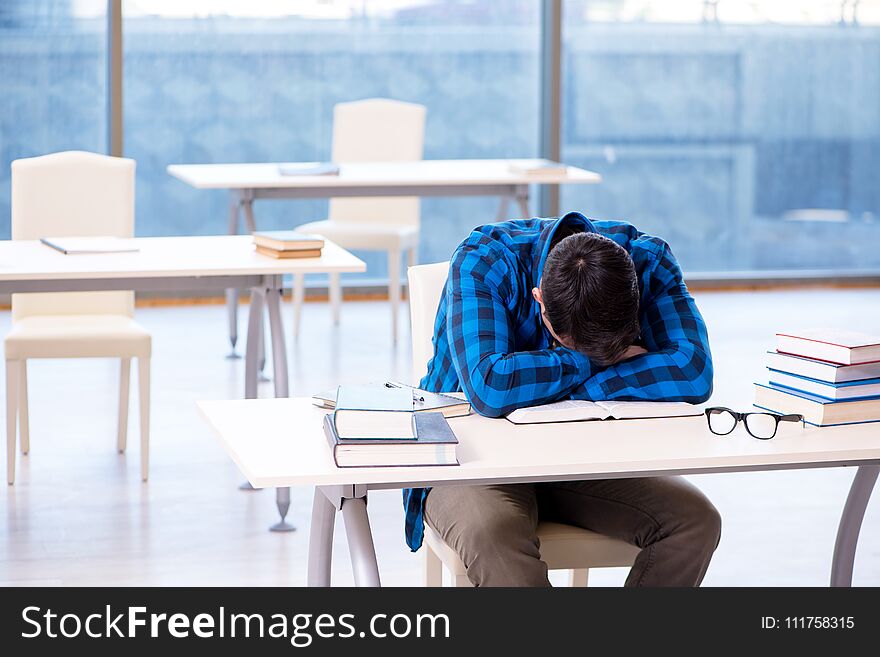 Student Studying In The Empty Library With Book Preparing For Ex