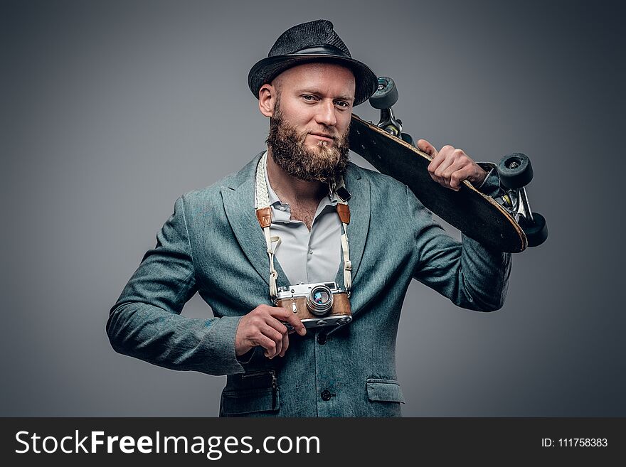 A man dressed in a grey jacket and felt hat holds an SLR photo c