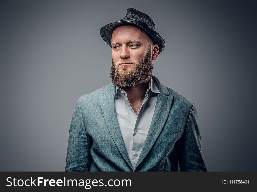 Stylish bearded male in a suit and felt hat on grey vignette background. Stylish bearded male in a suit and felt hat on grey vignette background.