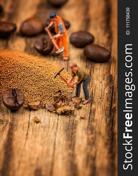 Miniature figures working on instant coffee macro photography on wood table. Miniature figures working on instant coffee macro photography on wood table