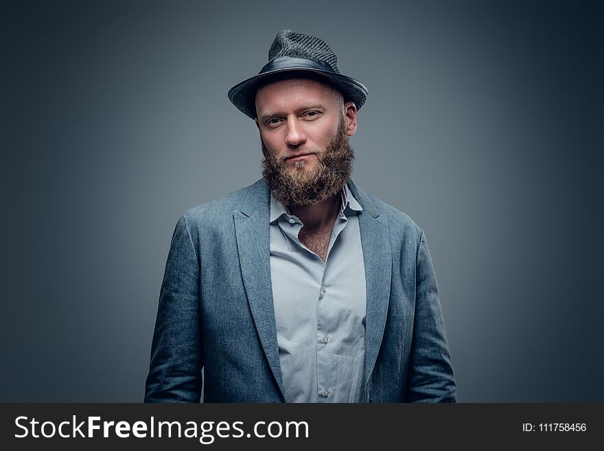 Stylish bearded male in a suit and felt hat on grey vignette background. Stylish bearded male in a suit and felt hat on grey vignette background.