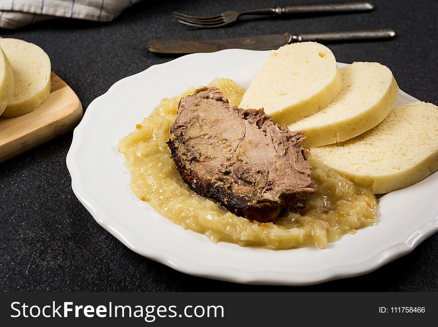 Traditional czech cuisine pork meat, dumpings and cabbage on dark stone table. Traditional czech cuisine pork meat, dumpings and cabbage on dark stone table