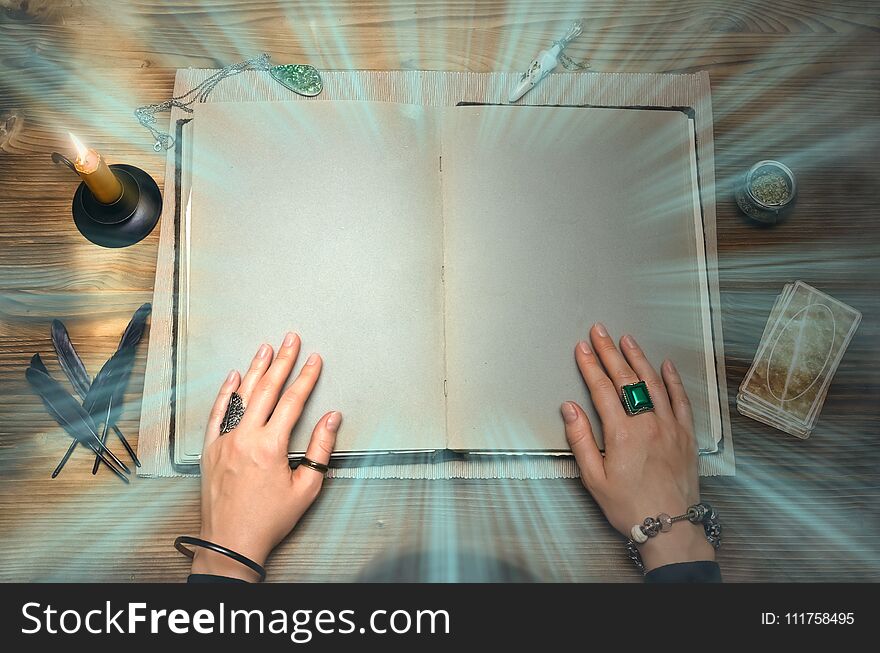 Book of magic with mystical light and copy space. Tarot cards on fortune teller desk table. Future reading. Woman witch reads a ancient magic scroll book and learn art of prediction on wooden table. Book of magic with mystical light and copy space. Tarot cards on fortune teller desk table. Future reading. Woman witch reads a ancient magic scroll book and learn art of prediction on wooden table.