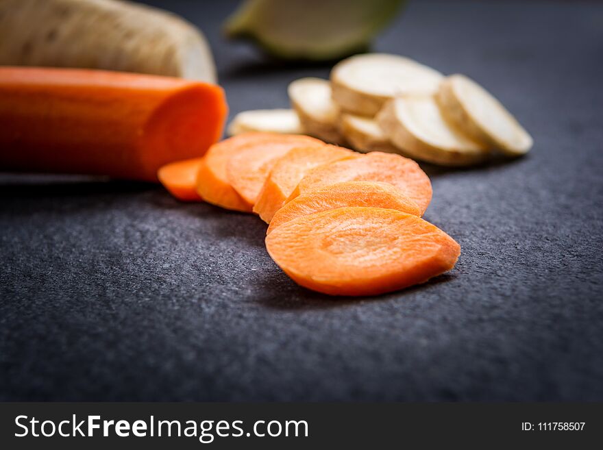 Cuts of carrot and parsley on dark stone table