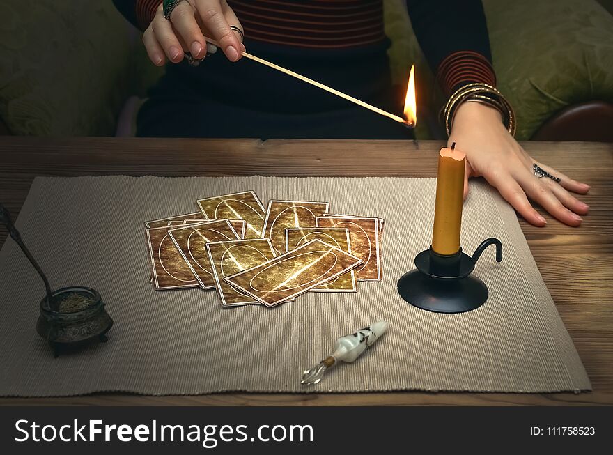 Tarot cards on fortune teller desk table. Future reading. Woman lights a candle by matches. Tarot cards on fortune teller desk table. Future reading. Woman lights a candle by matches.