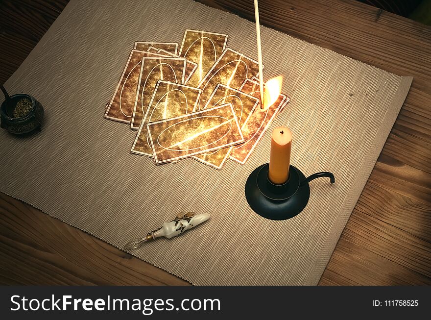 Tarot cards on fortune teller desk table. Future reading. Woman lights a candle by matches. Tarot cards on fortune teller desk table. Future reading. Woman lights a candle by matches.