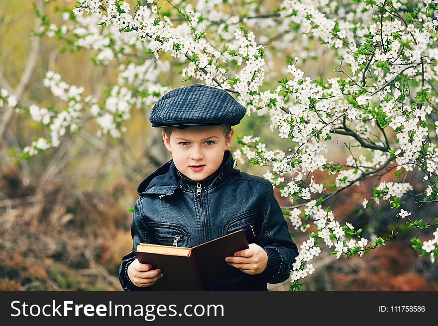 Boy in the spring flowering garden with a book in his hands. Boy in the spring flowering garden with a book in his hands