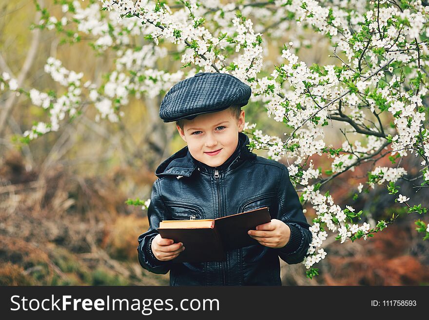 Boy in the spring flowering garden with a book in his hands. Boy in the spring flowering garden with a book in his hands