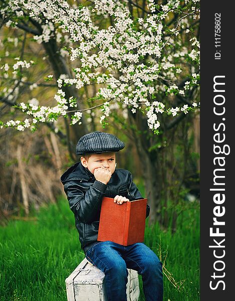 Boy in the spring flowering garden with a book in his hands. Boy in the spring flowering garden with a book in his hands