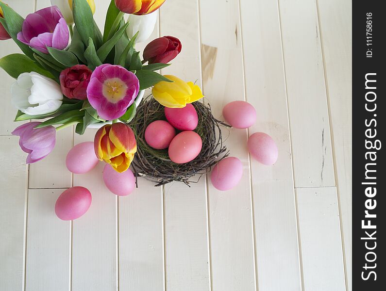 Easter. Pink easter eggs and tulips lie on a wooden background. Flat lay. Bird`s Nest. March 8. Pastel shades of pink. Wooden background. Conceptual photo. St. Patrick`s Day. Easter pink rabbit.