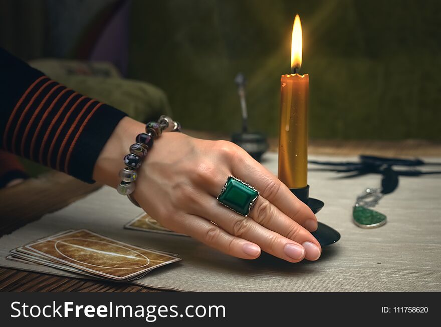 Tarot cards on fortune teller desk table. Future reading. Woman witch holds in her hands a burning candle. Tarot cards on fortune teller desk table. Future reading. Woman witch holds in her hands a burning candle.