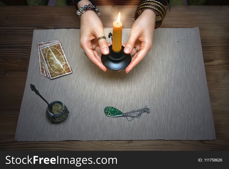 Tarot cards on fortune teller desk table. Future reading. Woman witch holds in her hands a burning candle. Tarot cards on fortune teller desk table. Future reading. Woman witch holds in her hands a burning candle.