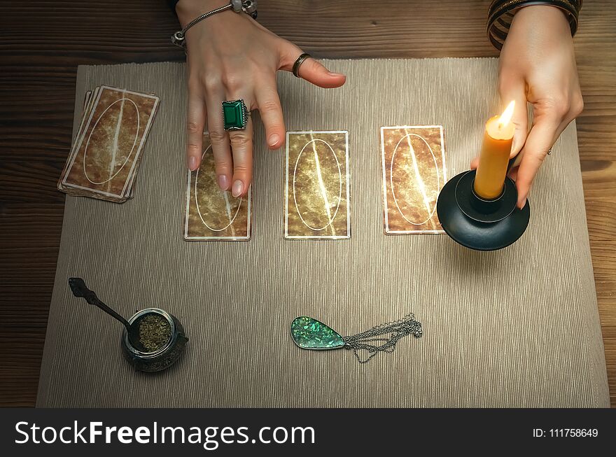 Tarot cards on fortune teller desk table. Future reading. Woman witch holds in her hands a burning candle. Tarot cards on fortune teller desk table. Future reading. Woman witch holds in her hands a burning candle.