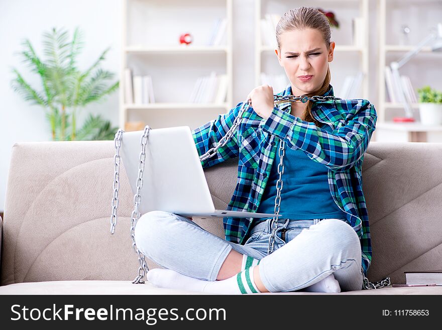 Chained female student with laptop sitting on the sofa