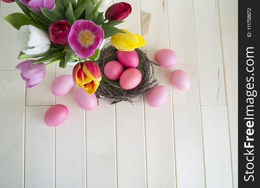 Easter. Pink Easter Eggs And Tulips Lie On A Wooden Background. Flat Lay.