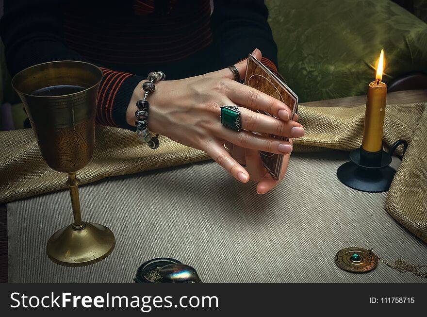 Tarot cards on fortune teller desk table. Future reading. Woman fortune teller holding in hands a deck of tarot cards and shuffles it. Tarot cards on fortune teller desk table. Future reading. Woman fortune teller holding in hands a deck of tarot cards and shuffles it.