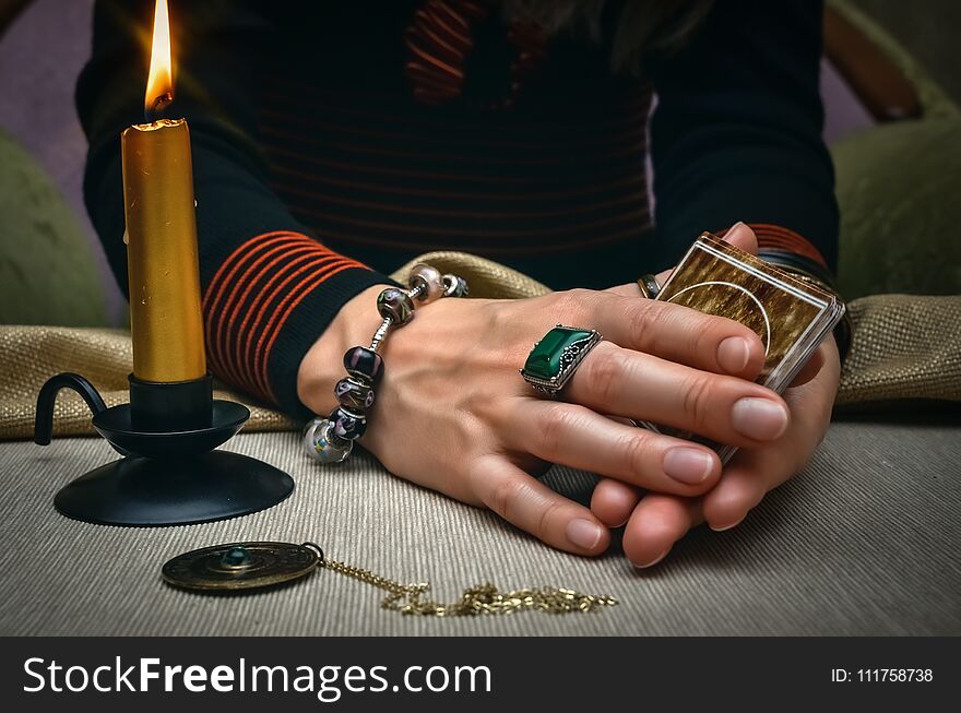 Tarot cards on fortune teller desk table. Future reading. Woman fortune teller holding in hands a deck of tarot cards and shuffles it. Tarot cards on fortune teller desk table. Future reading. Woman fortune teller holding in hands a deck of tarot cards and shuffles it.