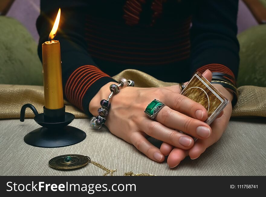 Tarot cards on fortune teller desk table. Future reading. Woman fortune teller holding in hands a deck of tarot cards and shuffles it. Tarot cards on fortune teller desk table. Future reading. Woman fortune teller holding in hands a deck of tarot cards and shuffles it.