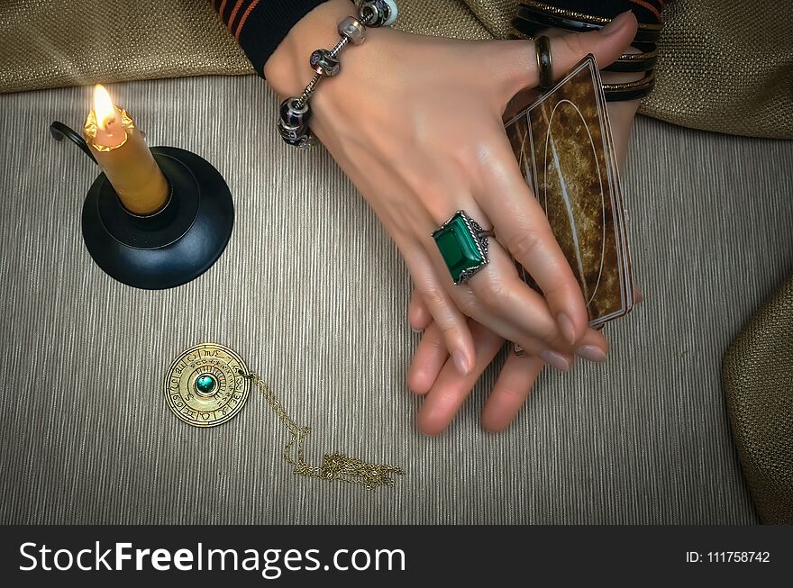 Tarot cards on fortune teller desk table. Future reading. Woman fortune teller holding in hands a deck of tarot cards and shuffles it. Tarot cards on fortune teller desk table. Future reading. Woman fortune teller holding in hands a deck of tarot cards and shuffles it.