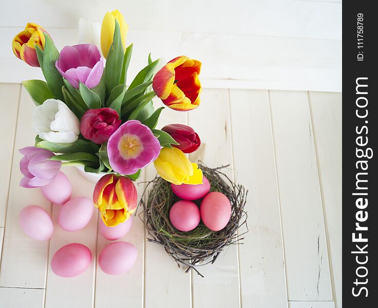 Easter. Pink easter eggs and tulips lie on a wooden background. Flat lay.
