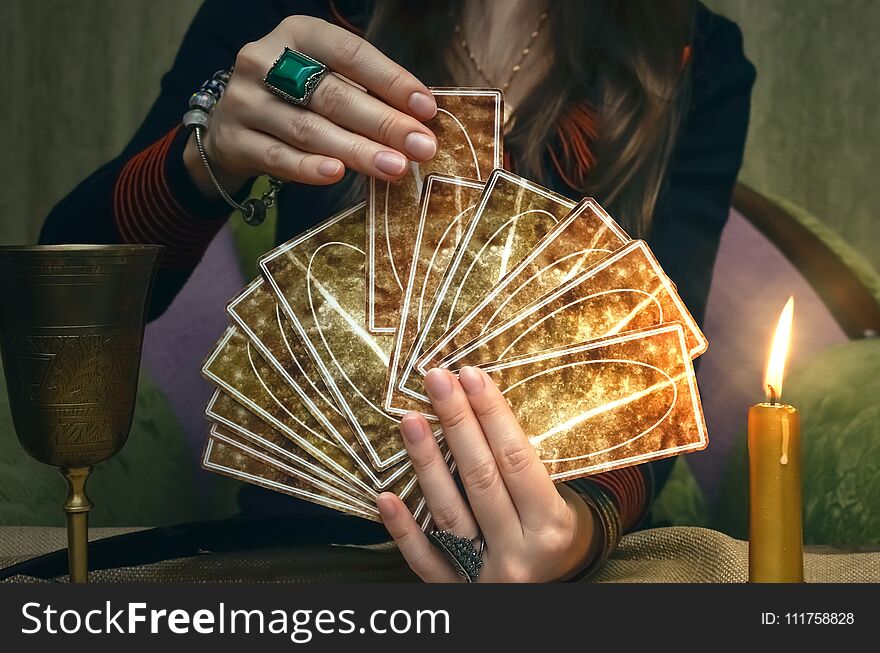 Tarot cards on fortune teller desk table. Future reading. Woman fortune teller holding and hands a deck of tarot cards and shuffles it. Tarot cards on fortune teller desk table. Future reading. Woman fortune teller holding and hands a deck of tarot cards and shuffles it.