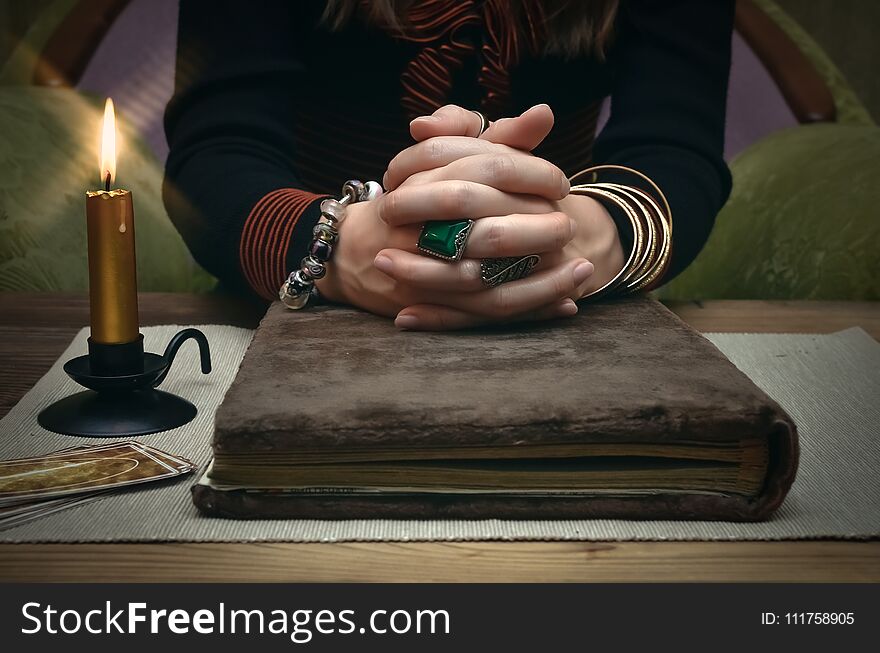 Book of magic. Tarot cards on fortune teller desk table. Future reading. Woman witch reads a ancient magic scroll book and learn art of prediction on wooden table. Book of magic. Tarot cards on fortune teller desk table. Future reading. Woman witch reads a ancient magic scroll book and learn art of prediction on wooden table.