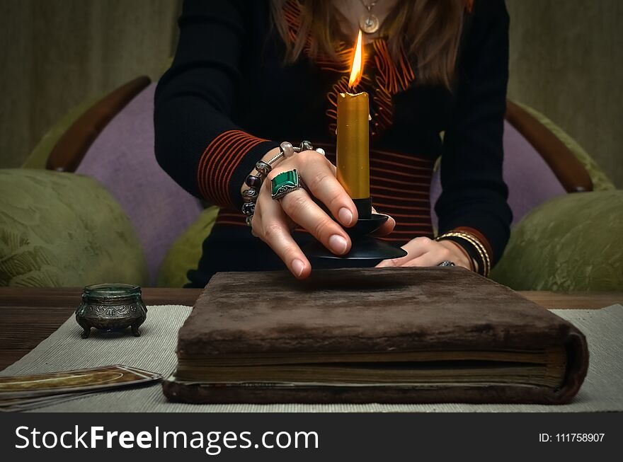 Book of magic. Tarot cards on fortune teller desk table. Future reading. Woman witch reads a ancient magic scroll book and learn art of prediction on wooden table. Book of magic. Tarot cards on fortune teller desk table. Future reading. Woman witch reads a ancient magic scroll book and learn art of prediction on wooden table.