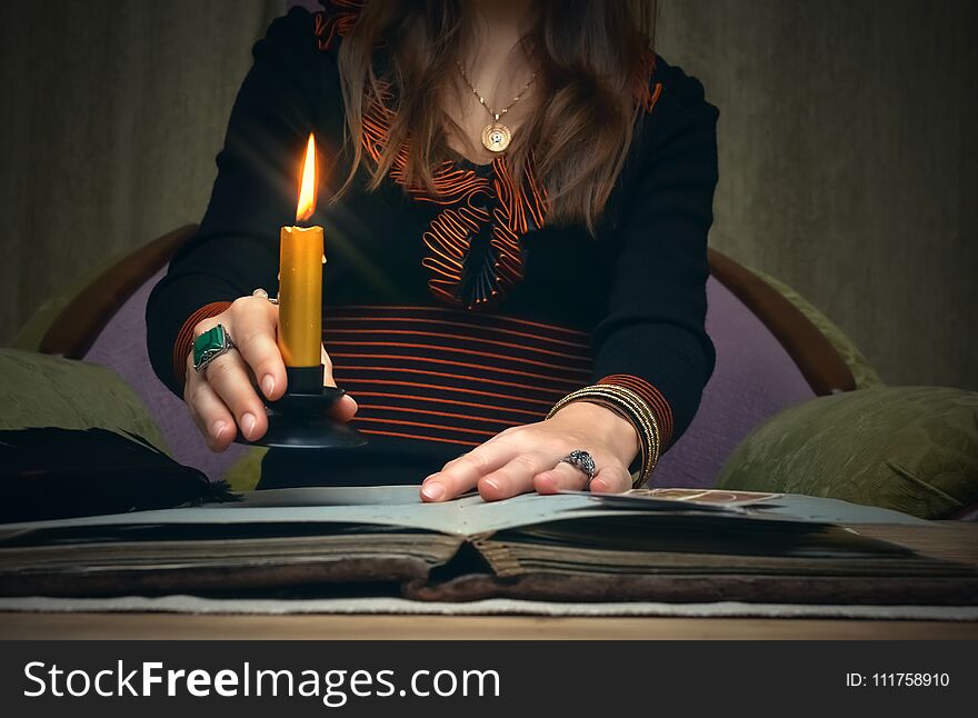 Tarot cards on fortune teller desk table. Future reading. Woman witch reads a ancient magic scroll book and learn art of prediction on wooden table. Tarot cards on fortune teller desk table. Future reading. Woman witch reads a ancient magic scroll book and learn art of prediction on wooden table.