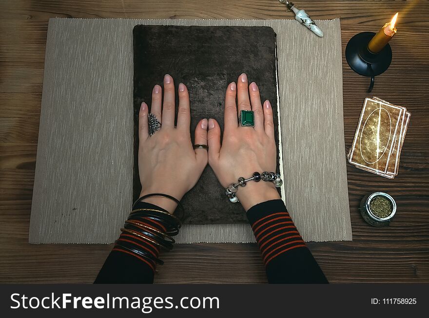 Book of magic. Tarot cards on fortune teller desk table. Future reading. Woman witch reads a ancient magic scroll book with copy space and learn art of prediction on wooden table. Book of magic. Tarot cards on fortune teller desk table. Future reading. Woman witch reads a ancient magic scroll book with copy space and learn art of prediction on wooden table.